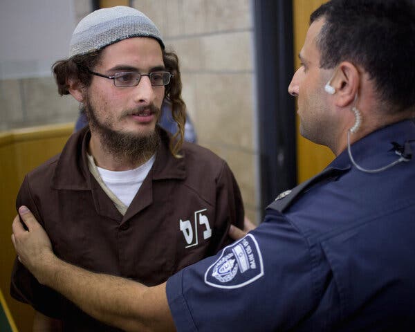 Meir Ettinger being directed by a person in a uniform with an earpiece.